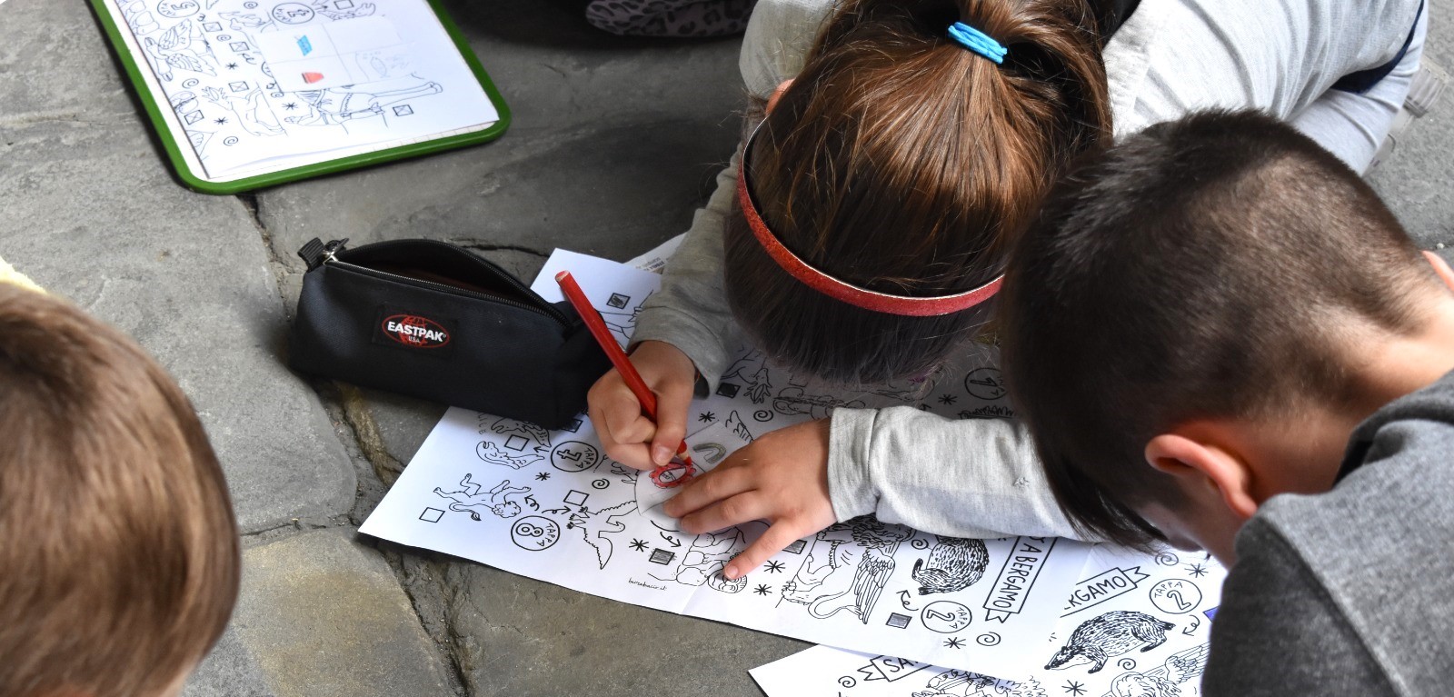 Due bambini stanno colorando il loro stemma personale durante il Safari Urbano di Bergamo, una visita guidata per famiglie.